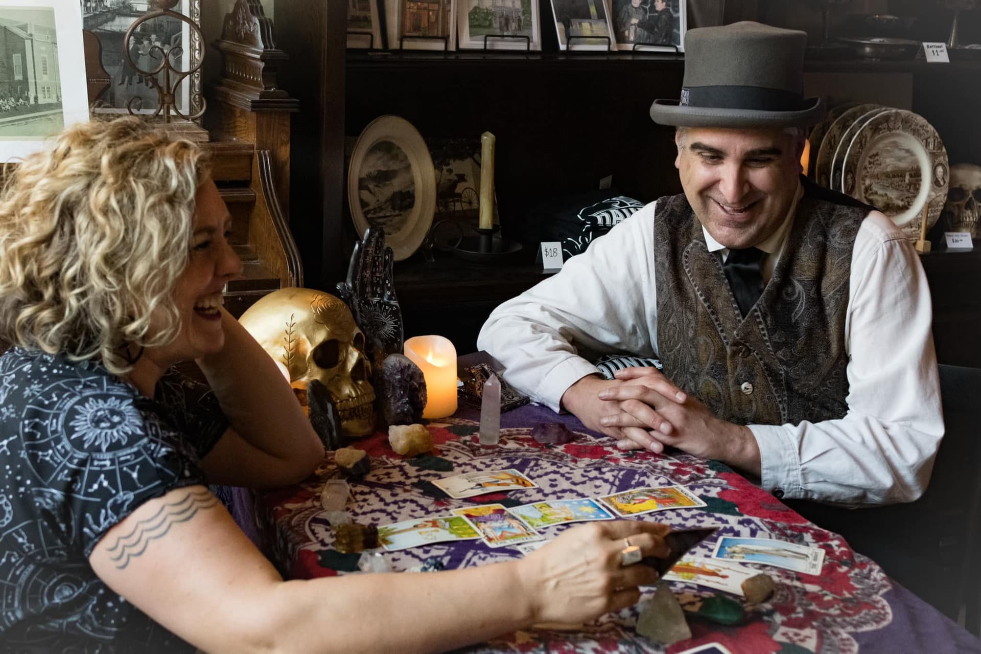 Holly Cole laughing with a client over a tarot spread at her candlelit reading table