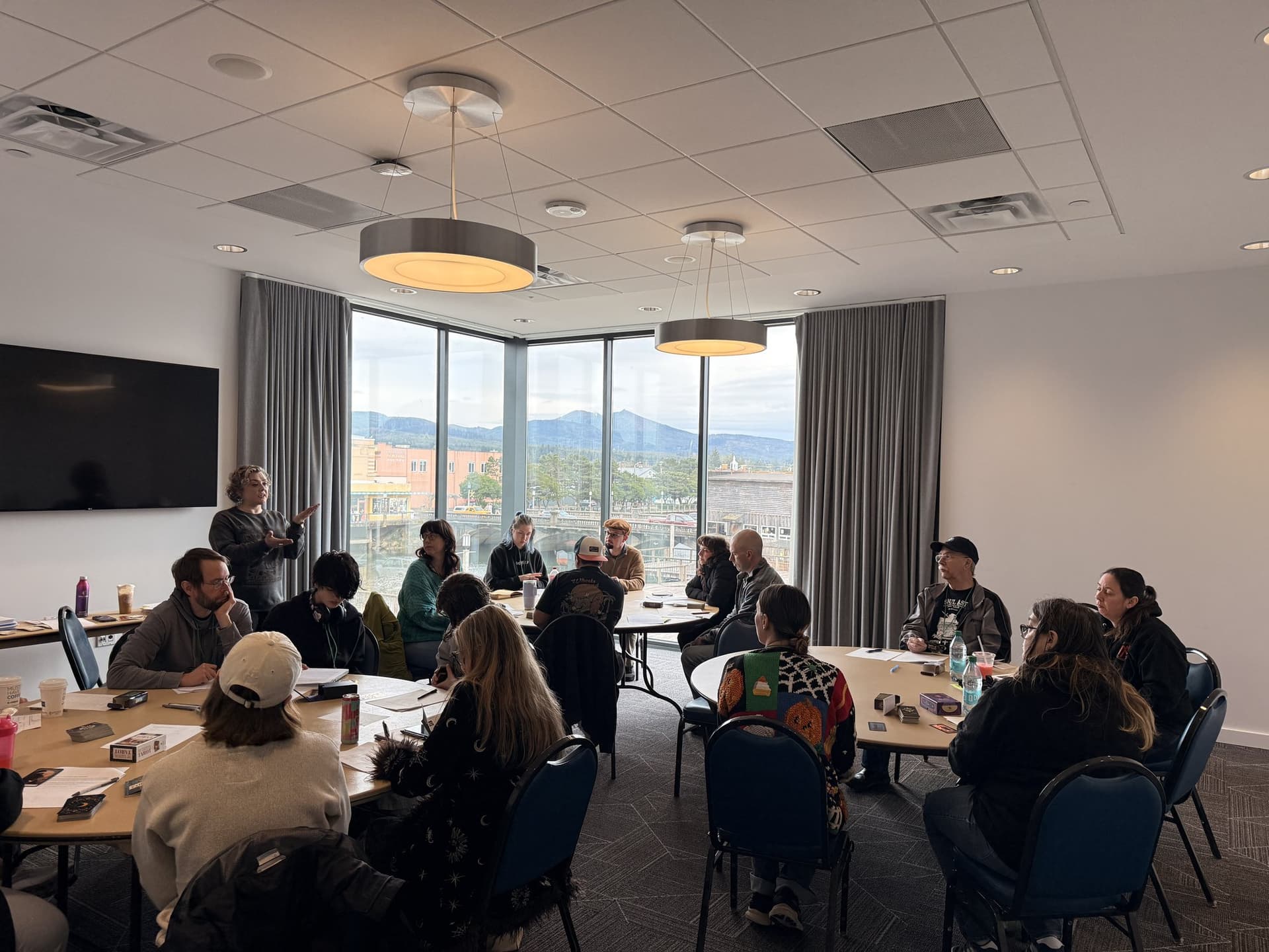 Holly Cole standing and teaching a full room of students at round tables during a group tarot class